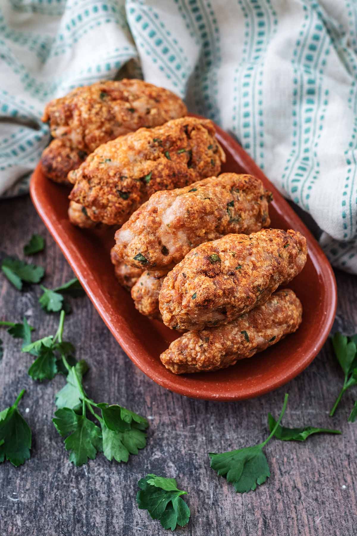 Nine koftas on a red oval plate.