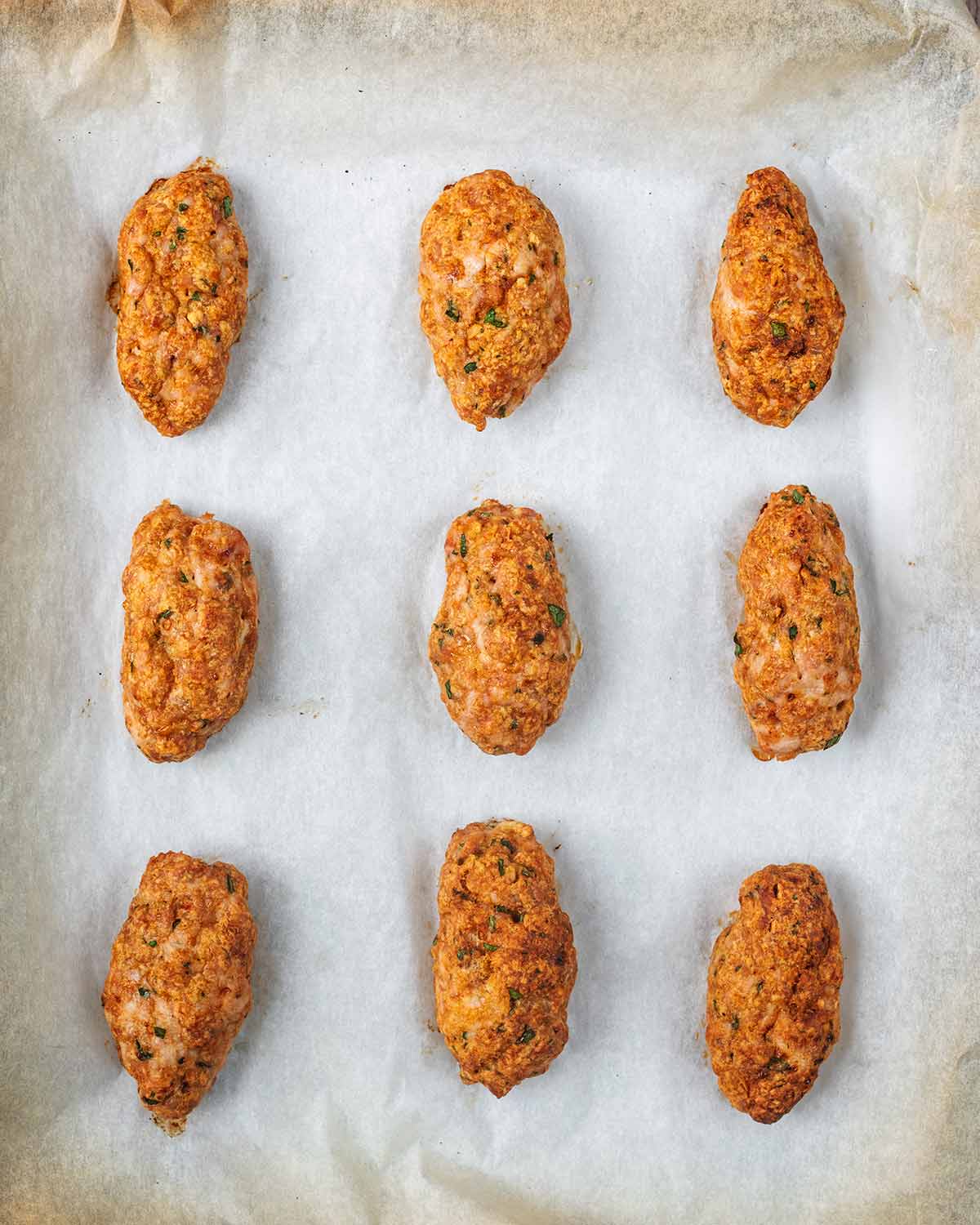 Nine cooked koftas on the baking sheet.