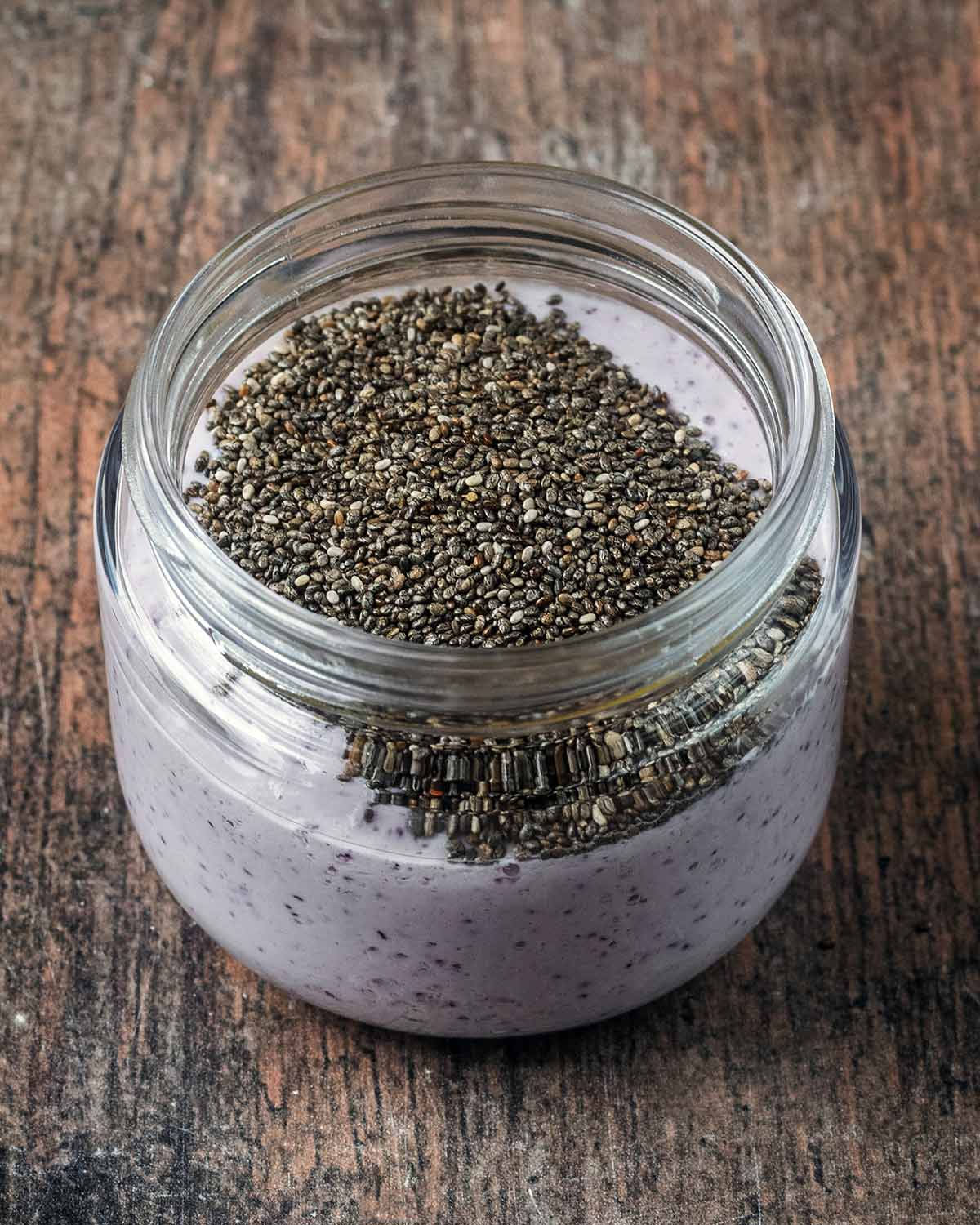 The blueberry mixture in a glass jar with chia seeds added.