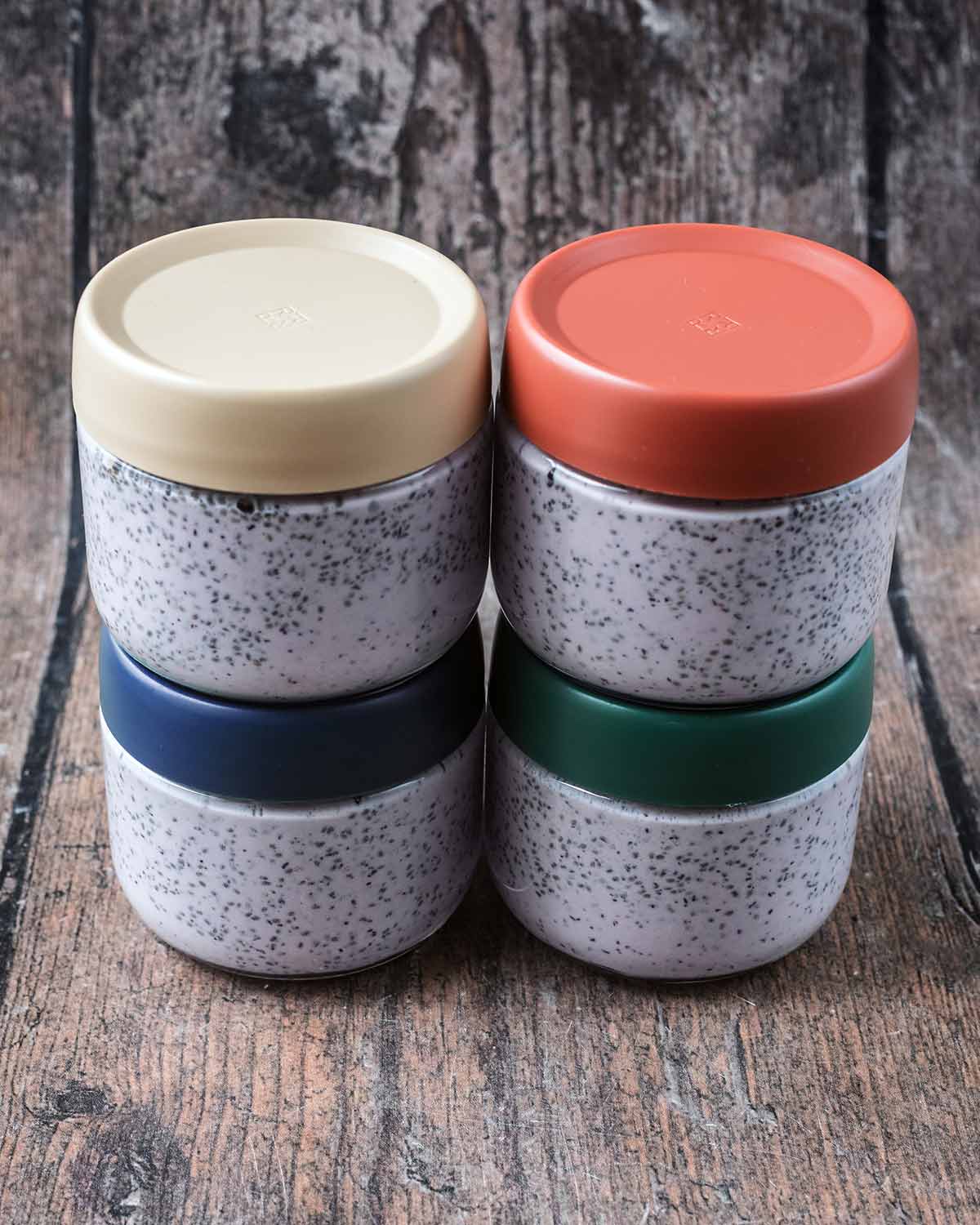 Four jars with different coloured lids each containing chia pudding.