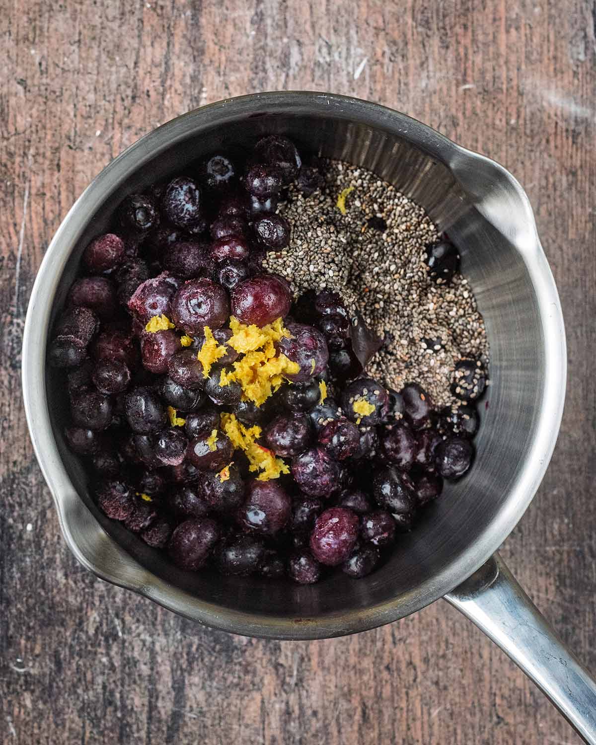 A saucepan containing blueberries, chia seeds and lemon zest.