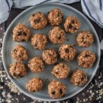 Seventeen dark chocolate chip energy balls on a round plate.