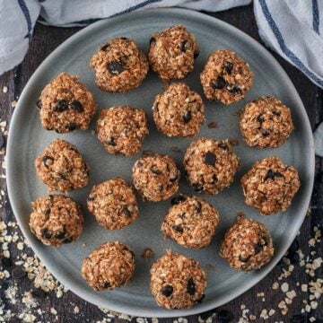 Seventeen dark chocolate chip energy balls on a round plate.