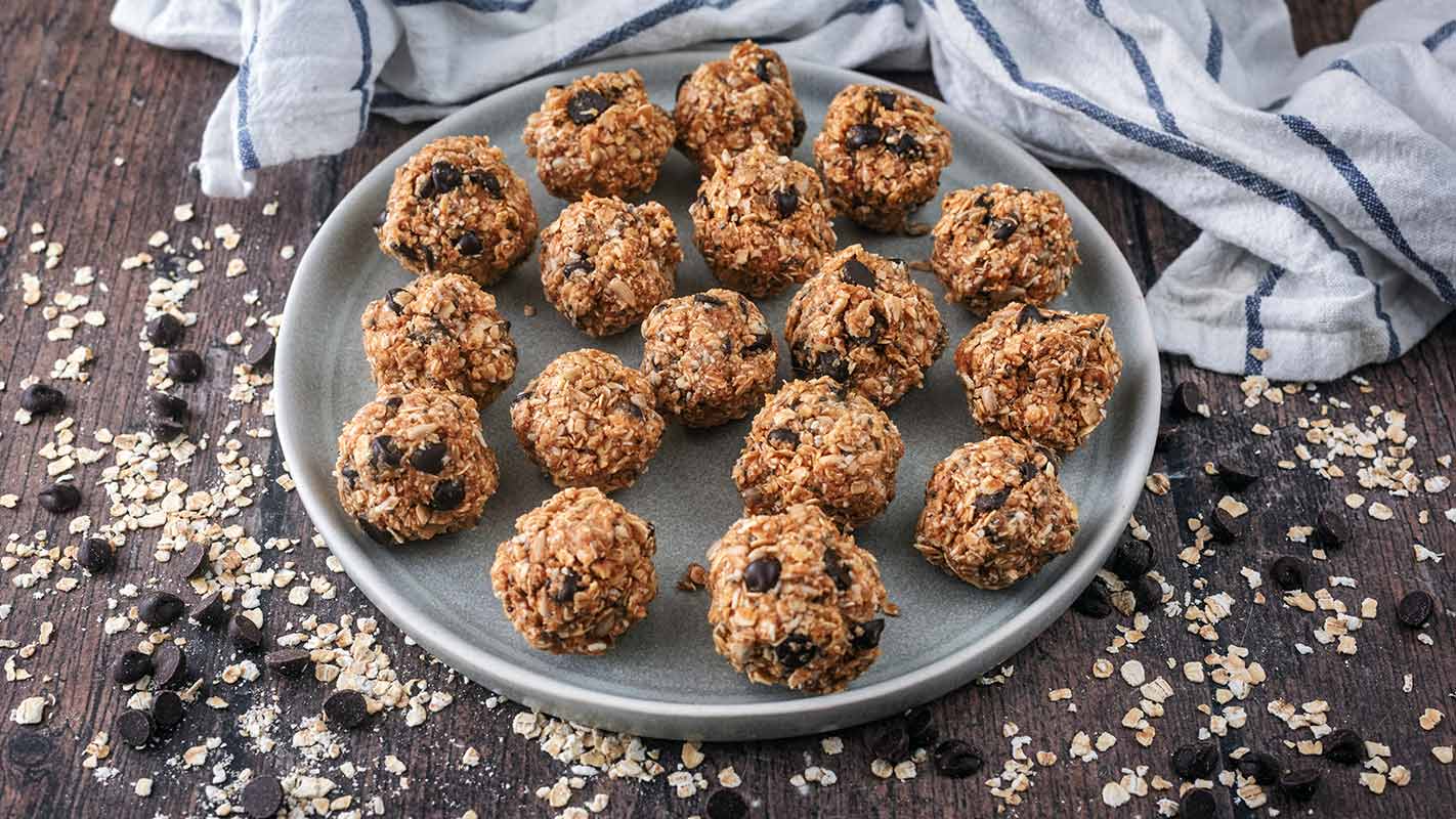 Dark chocolate chip energy balls on a plate in front of a towel.