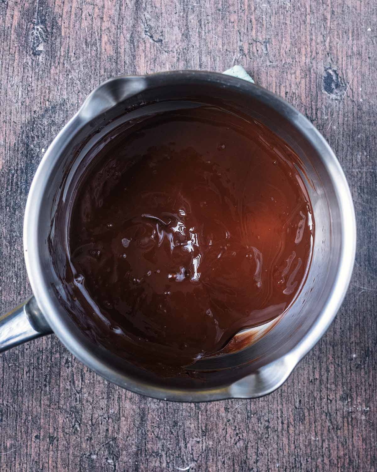 Melted chocolate in a silver saucepan.