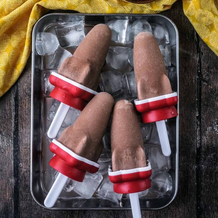 Four high protein chocolate fudge popsicles on a tray of ice.