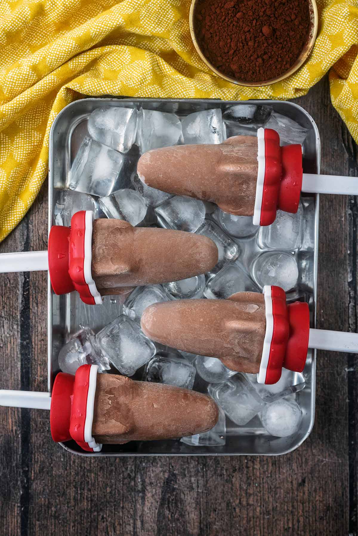 Four rocket shaped popsicles on a tray of ice cubes.