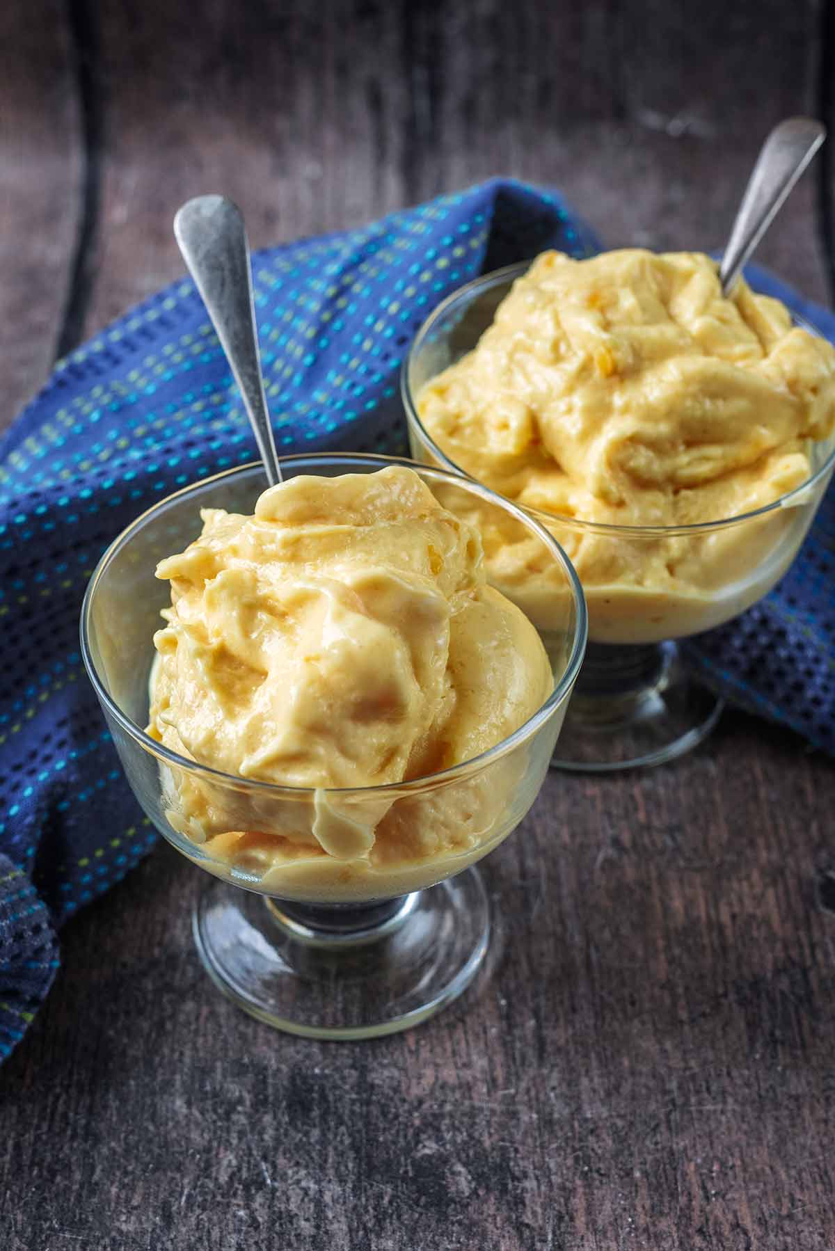 Two serving glasses containing mango frozen yogurt.