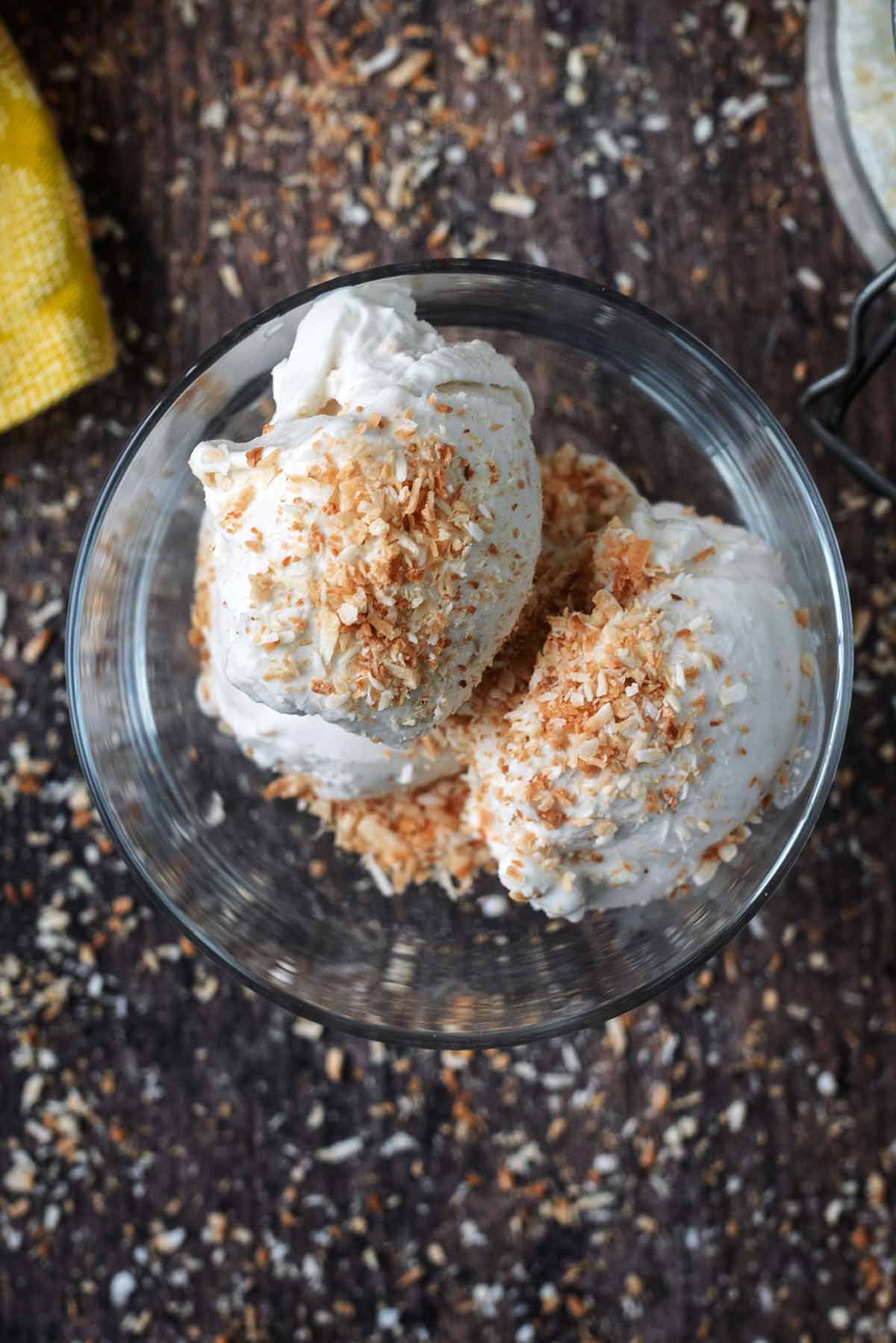 Two balls of coocnut ice cream topped with toasted desiccated coconut.