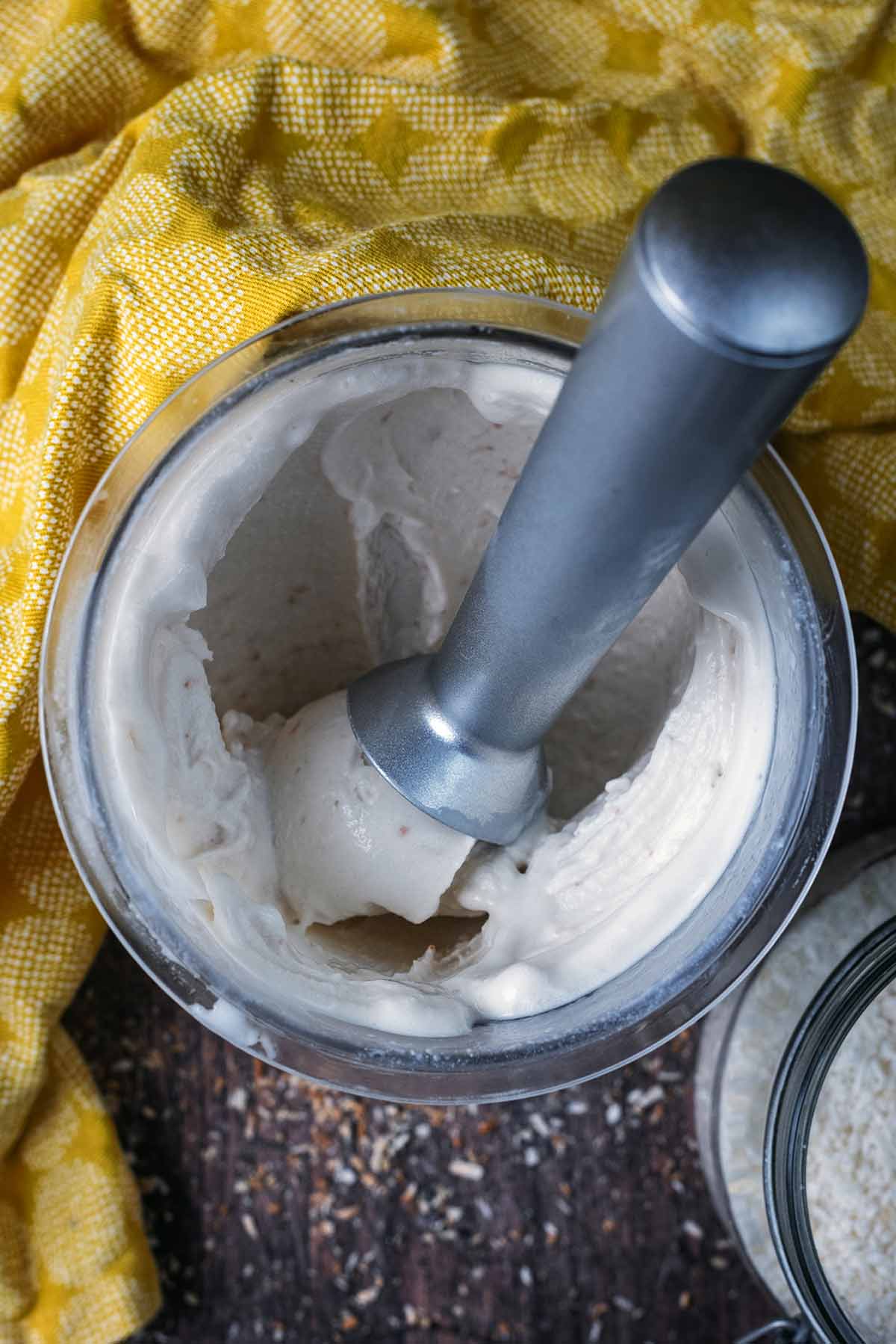 An ice cream scoop in a tup of coconut ice cream.