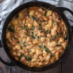 Creamy butter bean gnocchi in a large black pan.