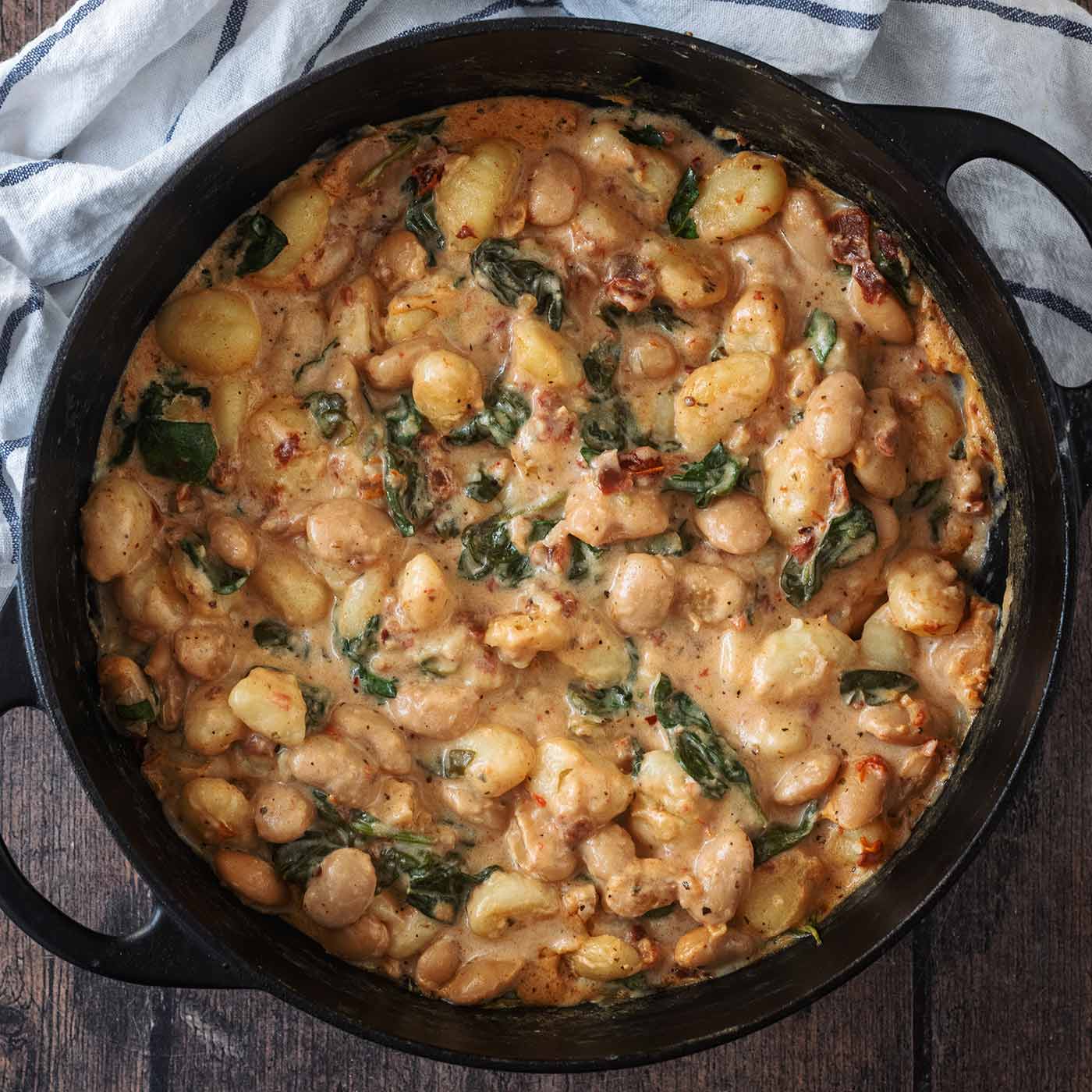 Creamy butter bean gnocchi in a large black pan.