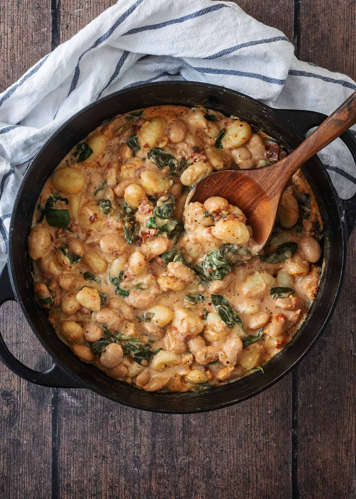 A large pan of white bean gnocchi next to a striped towel.