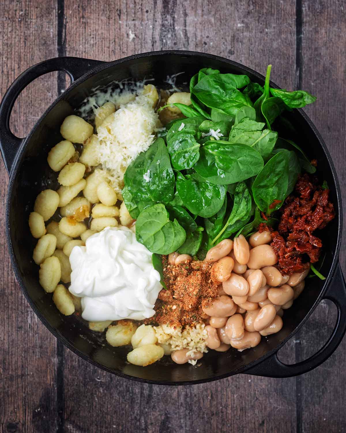Beans, spinach, tomatoes, cheese, cream and seasoning added to the pan.