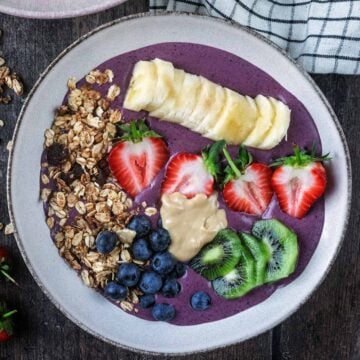 A high protein acai bowl on a wooden surface.