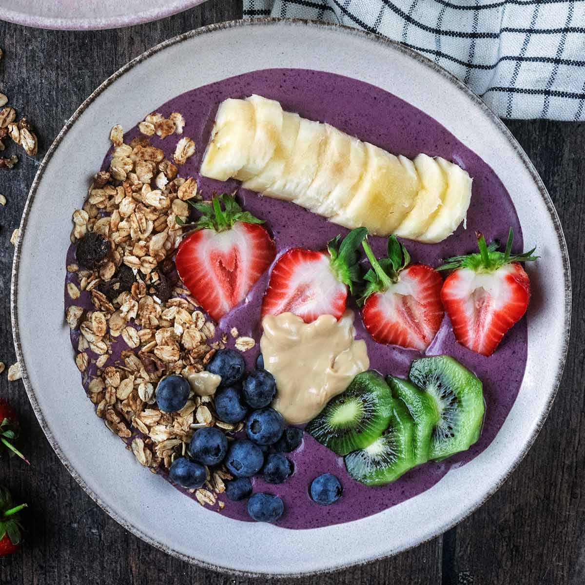 A high protein acai bowl on a wooden surface.