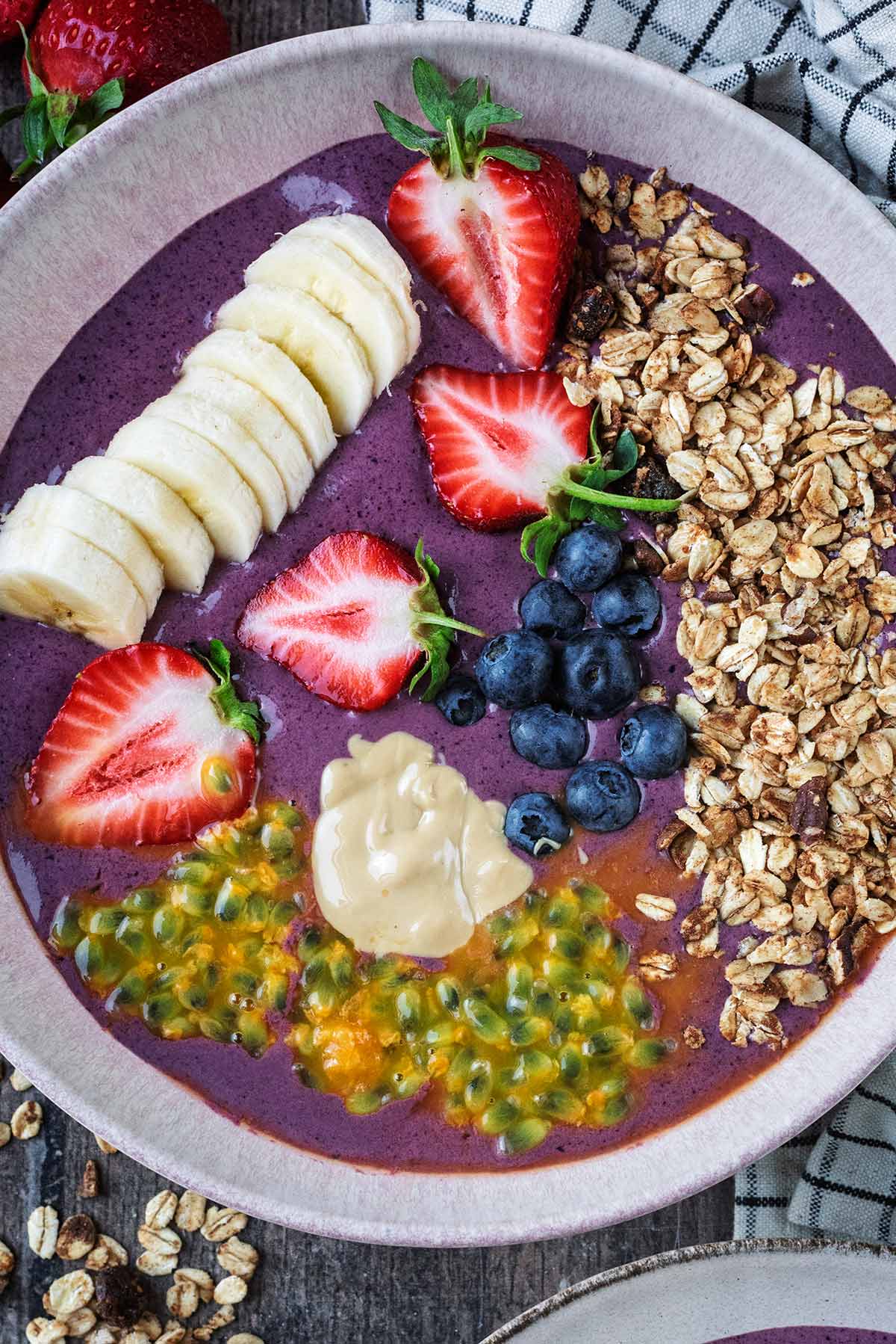 Acai bowl topped with banana slices, granola, berries and passionfruit seeds.