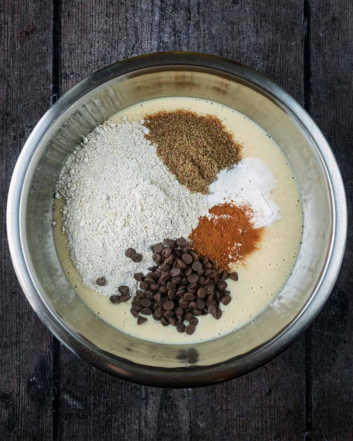 Flour, seeds, spices and chocolate chips added to the bowl.