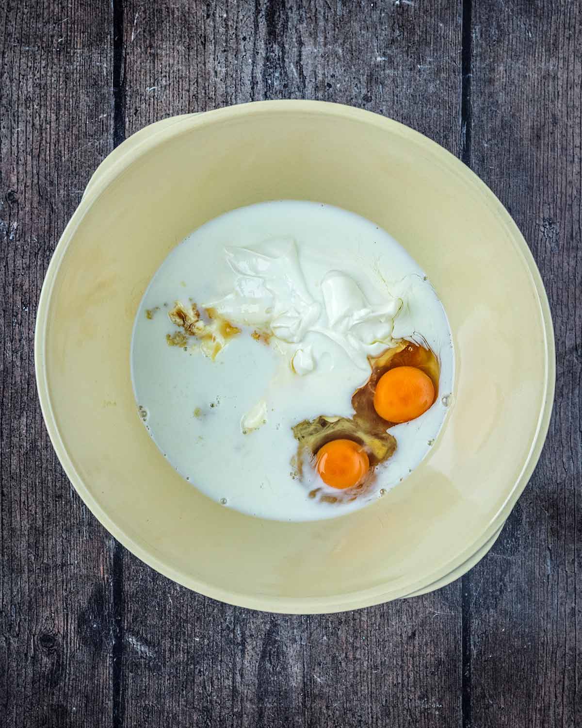 Eggs, milk, yogurt and vanilla in a large mixing bowl.