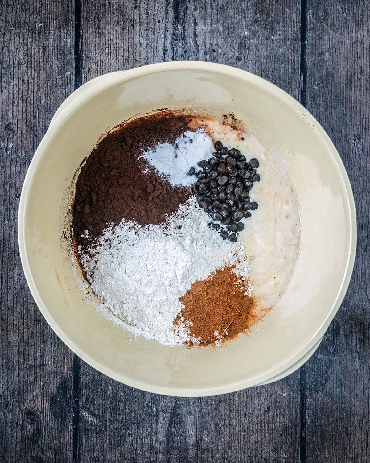 Flour, cocoa, cinnamon and chocolate chips added to the bowl.