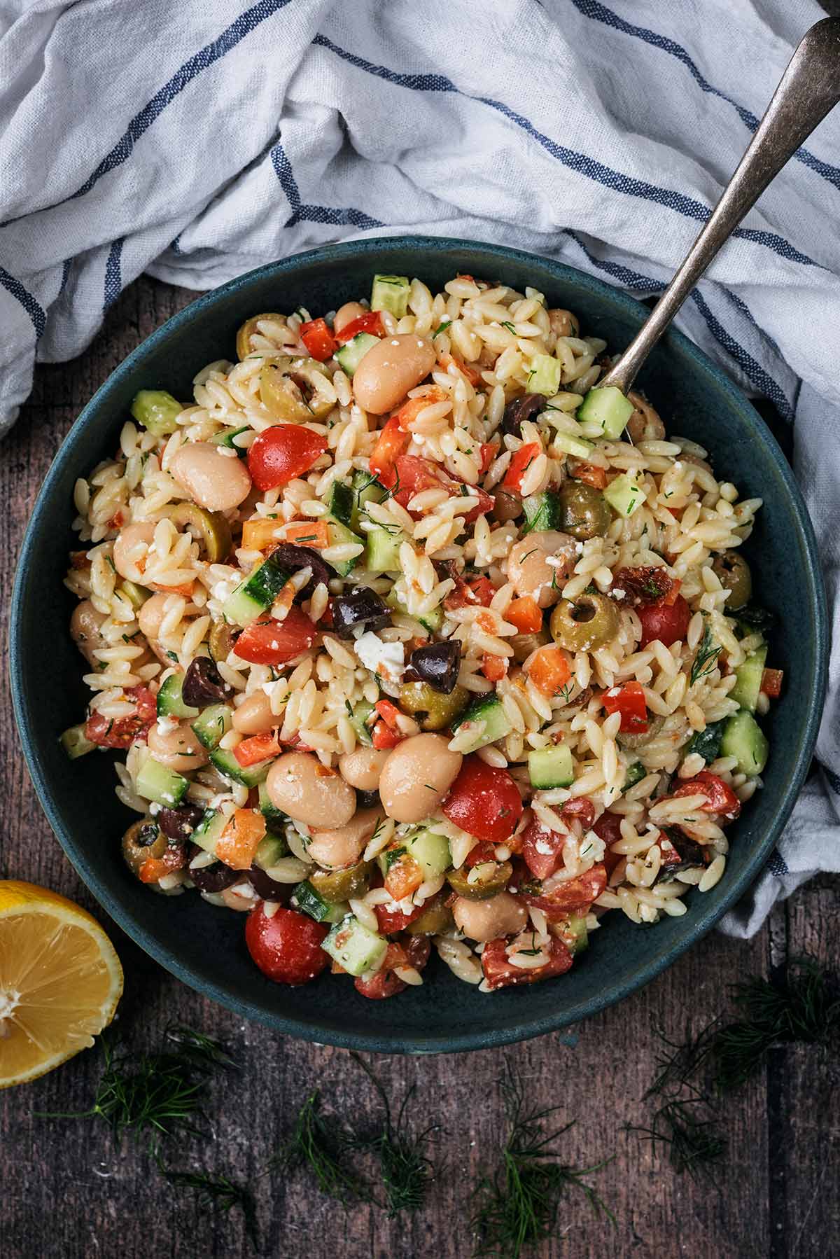 A bowl of pasta salad next to a striped towel.