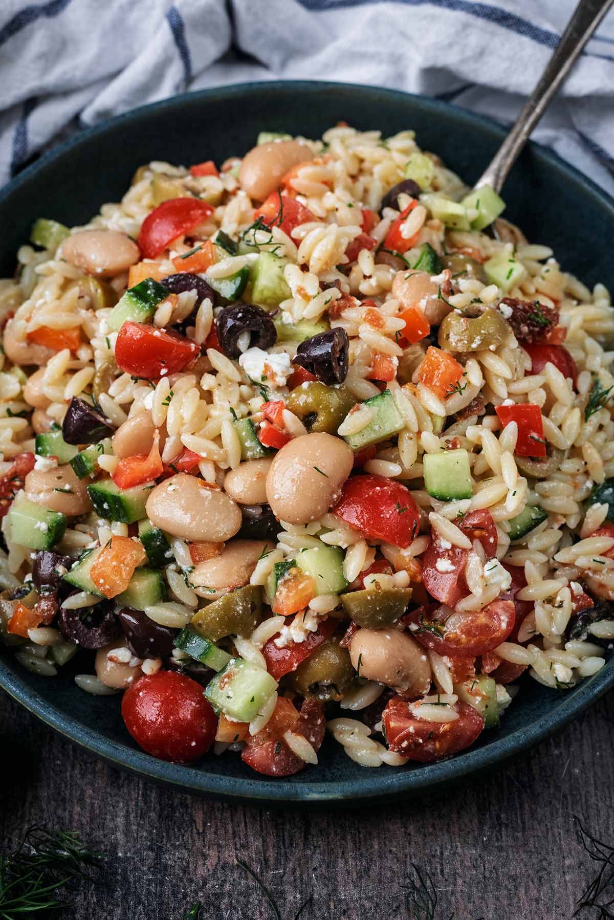 A bowl of orzo salad in front of a towel.
