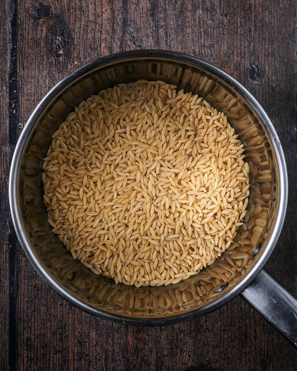 Uncooked orzo in a saucepan.