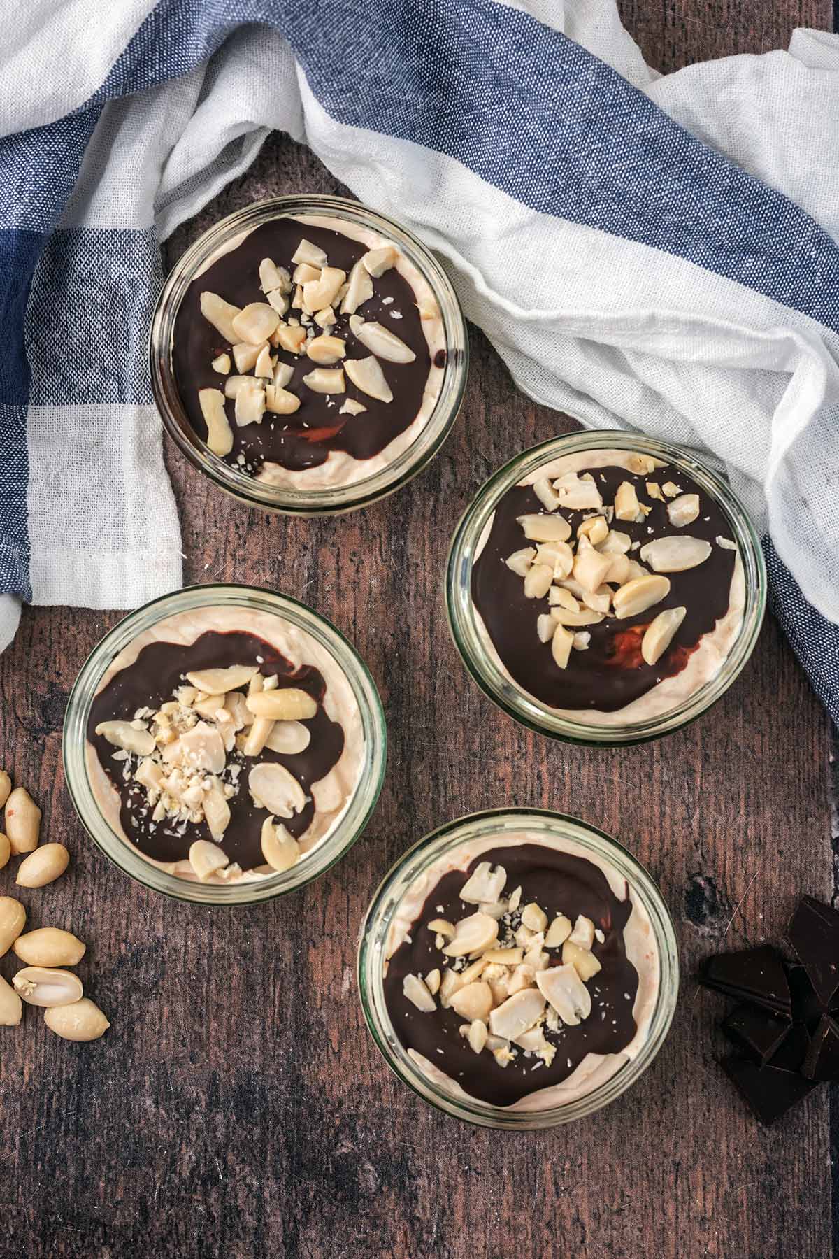 Four glass ramekins full ot yogurt and topped with chocolate and chopped peanuts.