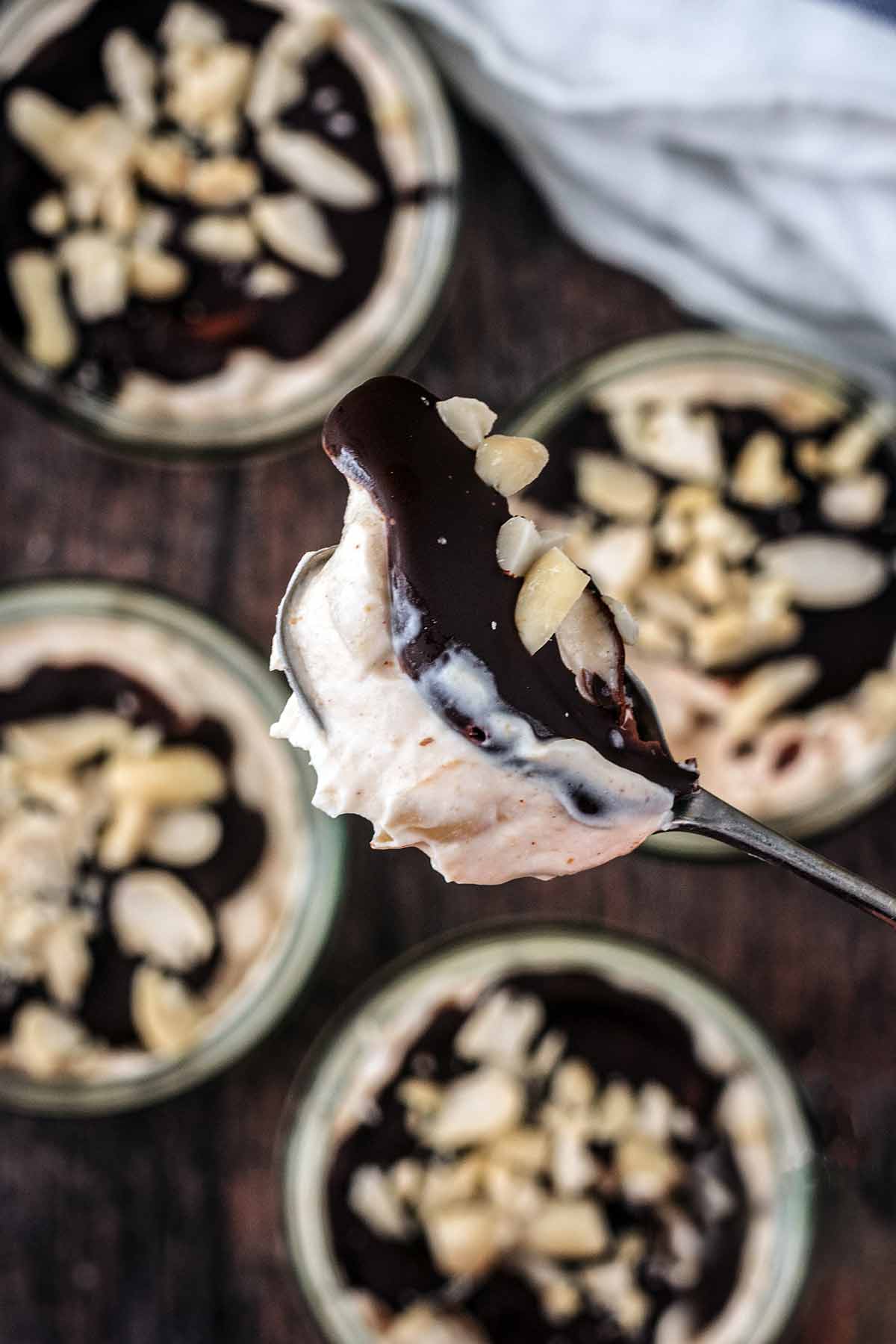 A spoon lifting a chocolate topped spoonful of yogurt out of a ramekin.