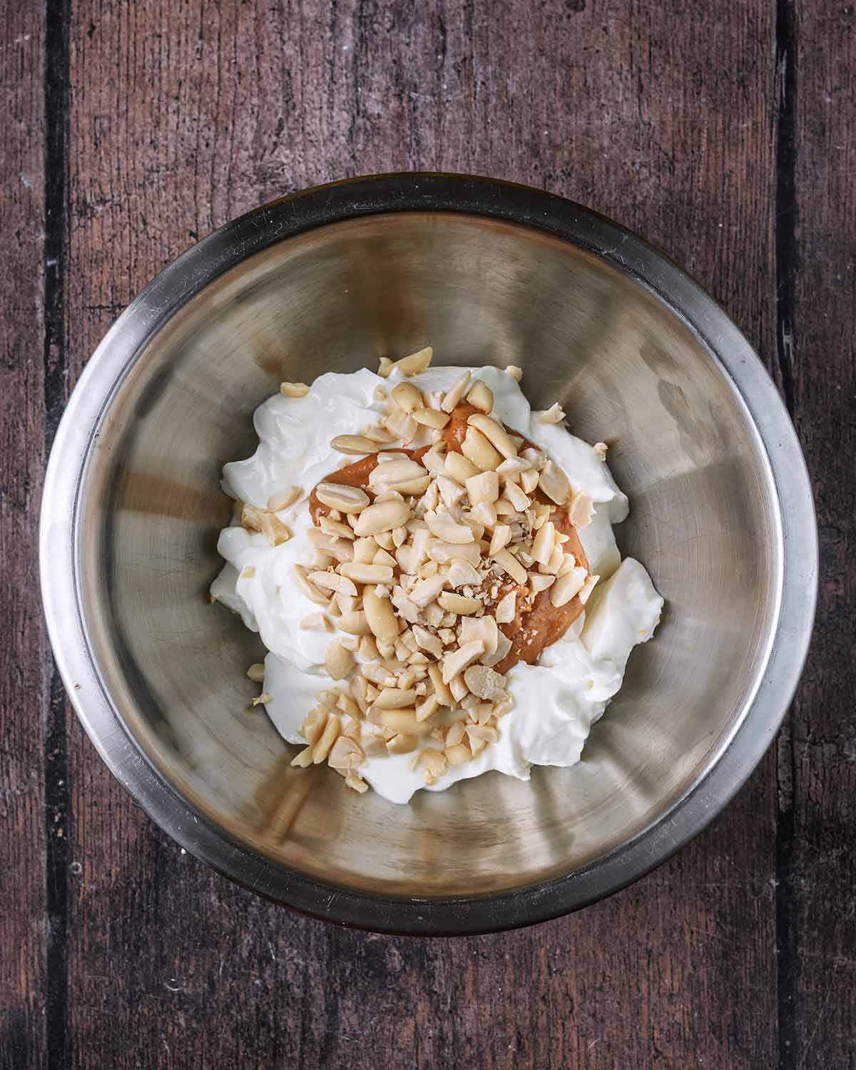 Yogurt, peanut butter and peanuts in a mixing bowl.