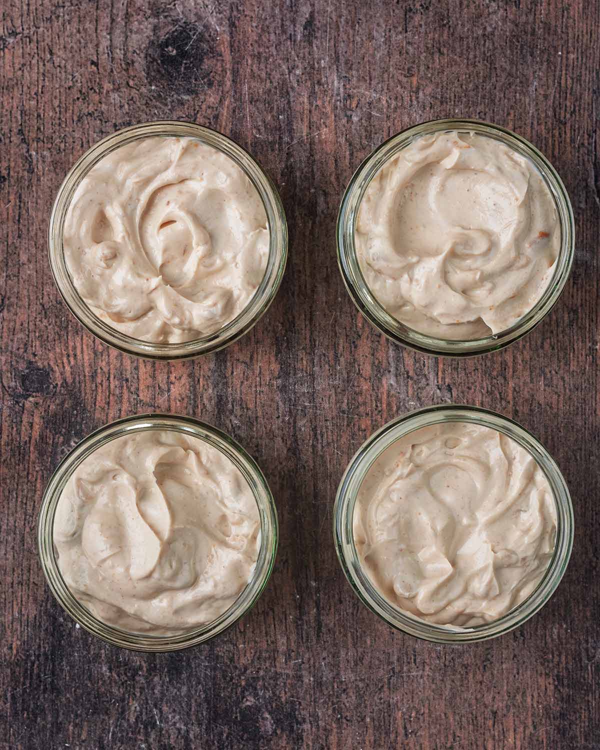 Four glass ramekins containing the peanut yogurt mixture.