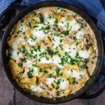 A large black pan full of chicken and broccoli lasagna.