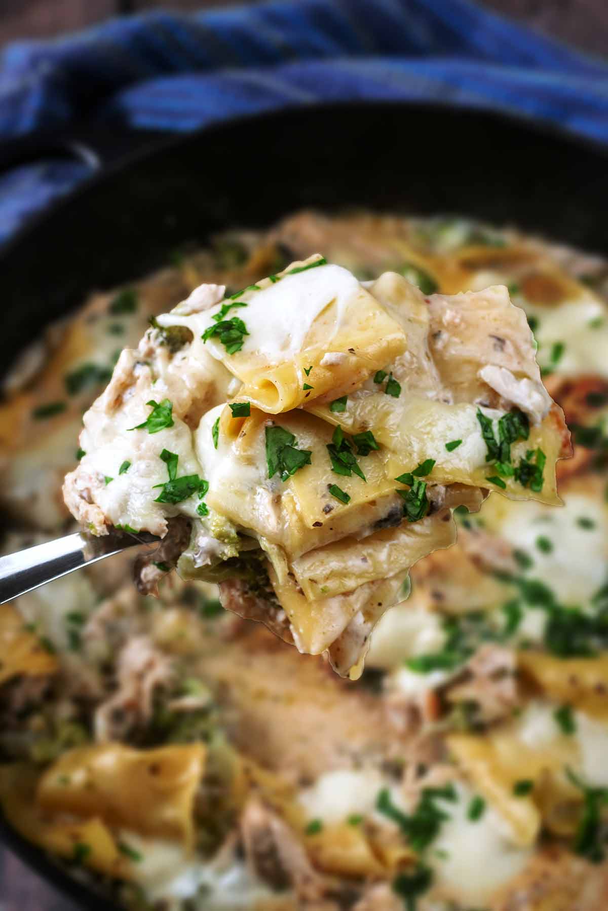 A portion of lasagna being lifted from a pan.