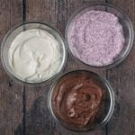 Three different types of flavoured yogurt in glass containers.