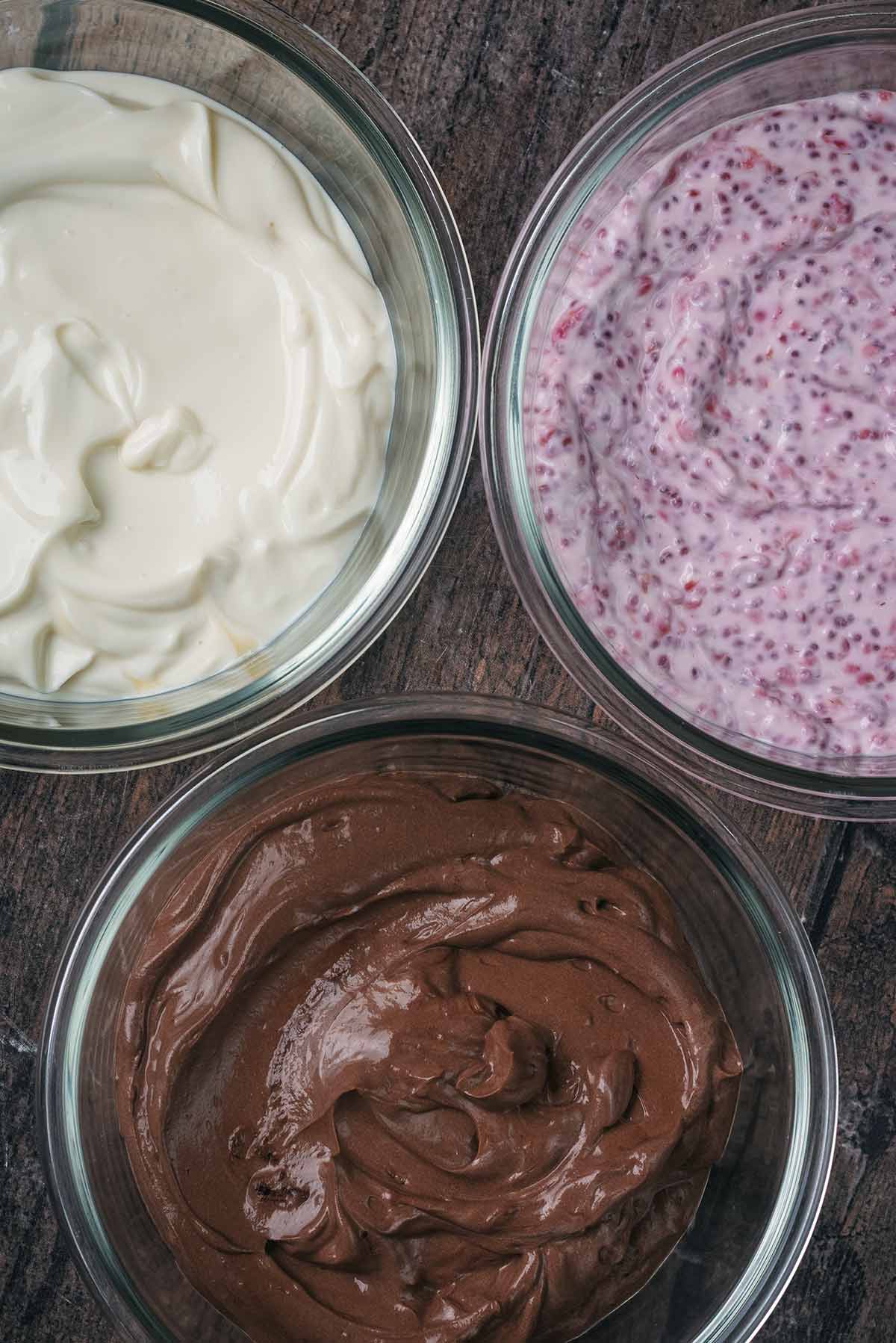 Three glass containers each containing a different flavour of yogurt.