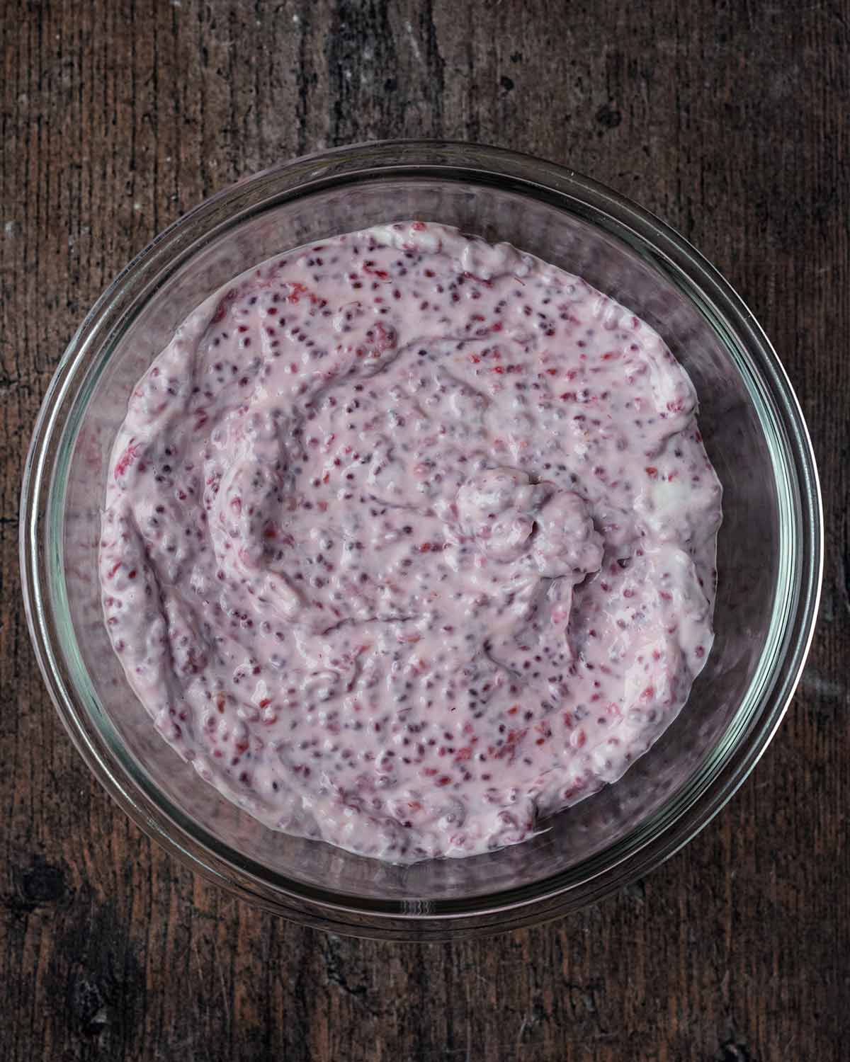 Raspberry chia yogurt in a glass container.