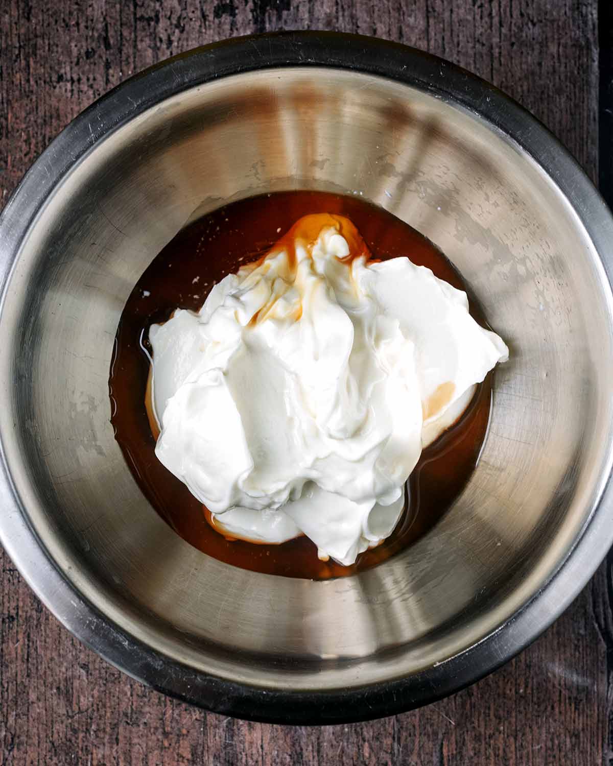 A mixing bowl containing yogurt and vanilla extract.