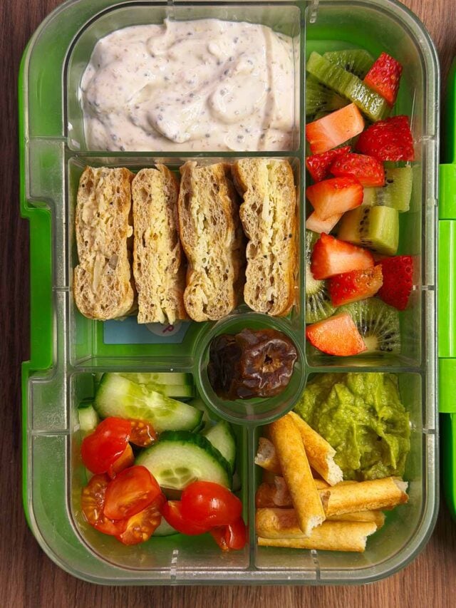 A compartment lunchbox containing a sandwich, salad, yogurt and fruit.
