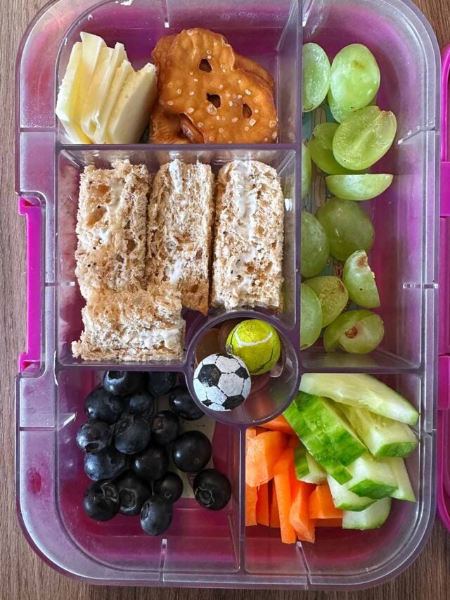 A compartment lunchbox containing a sandwich, fruit, veg, cheese, crackers and chocolate.
