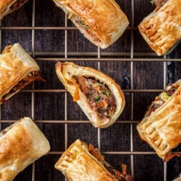 Sausage rolls with vegetables on a cooling rack.