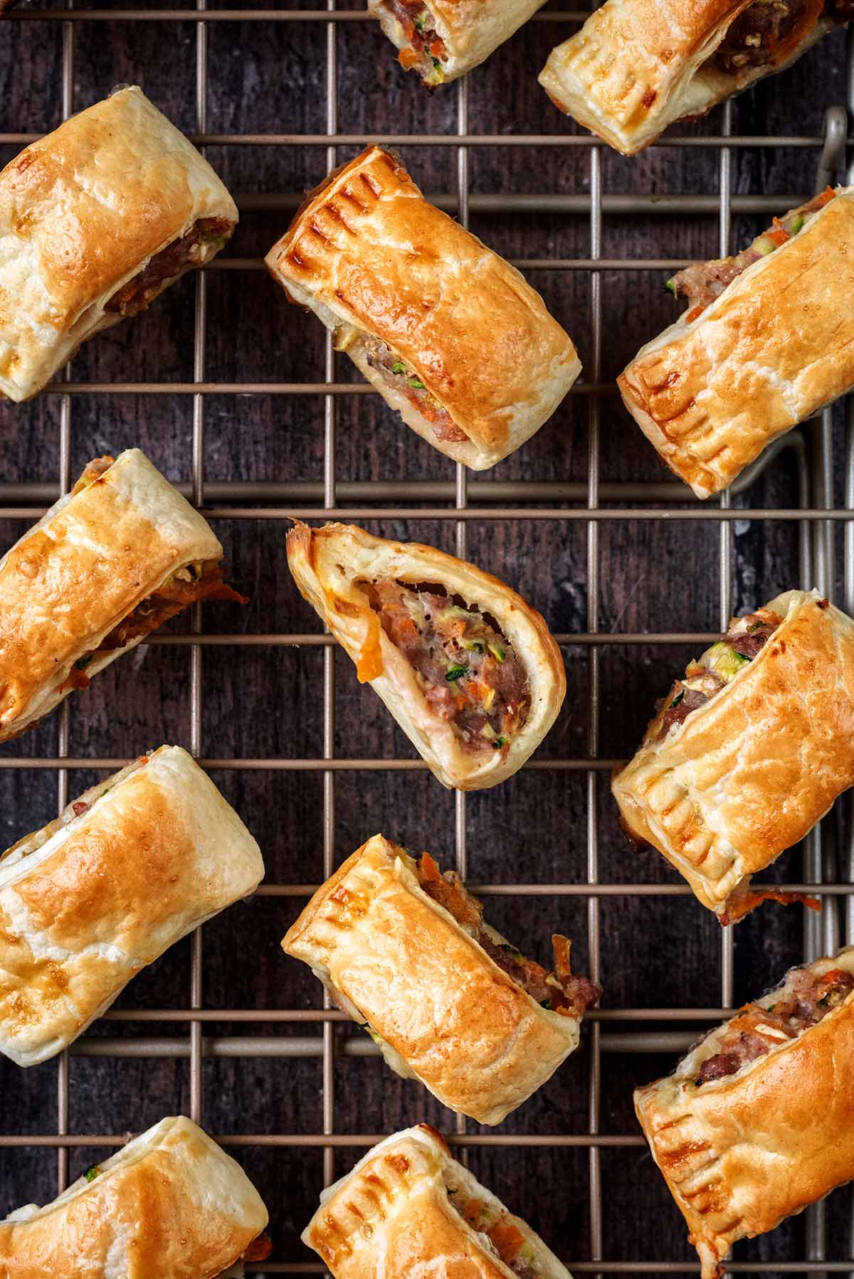 Twelve mini sausage rolls on a cooling rack.