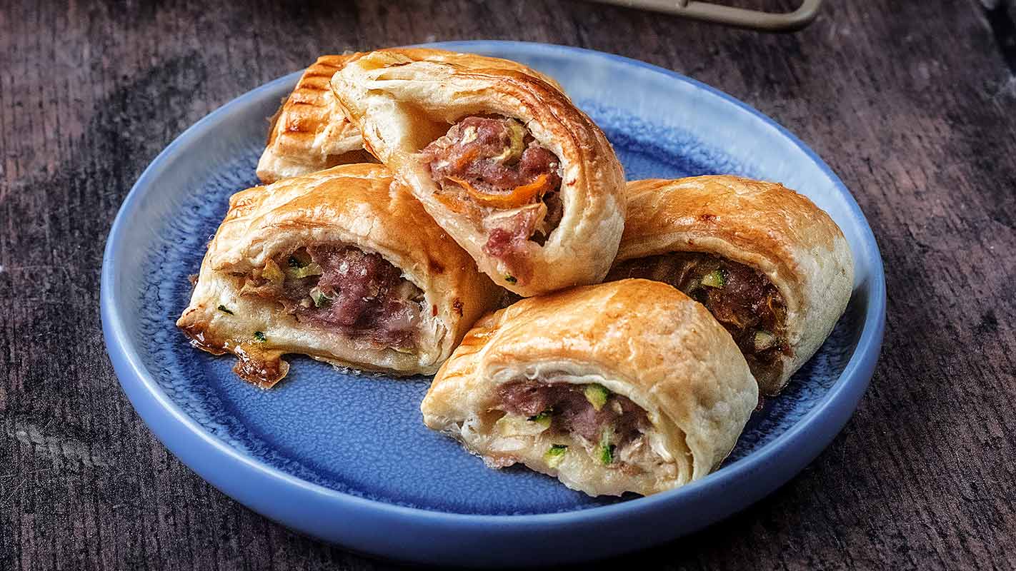 Sausage rolls with vegetables on a plate on a wooden surface.