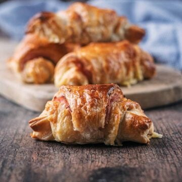 Mini ham and cheese puff pastry croissant with more in the background.