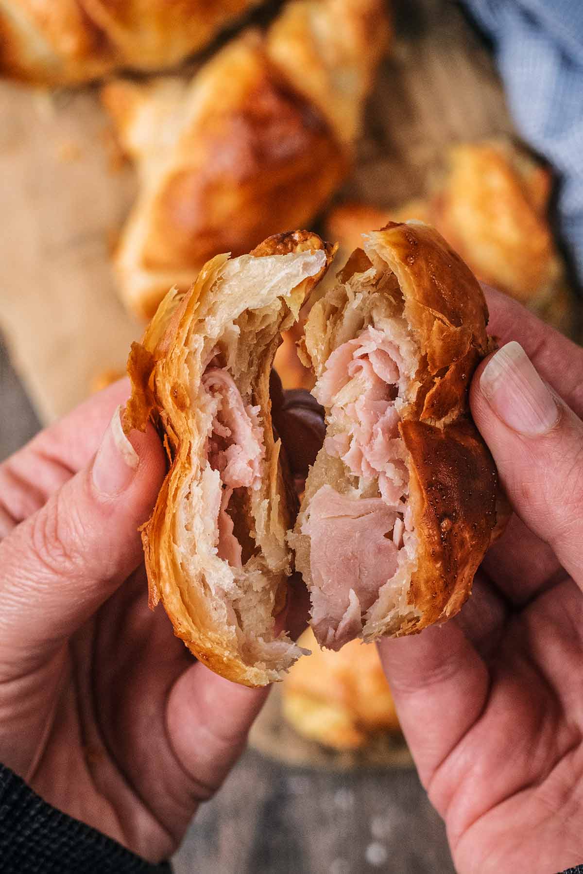 A ham and cheese croissant broken in half.