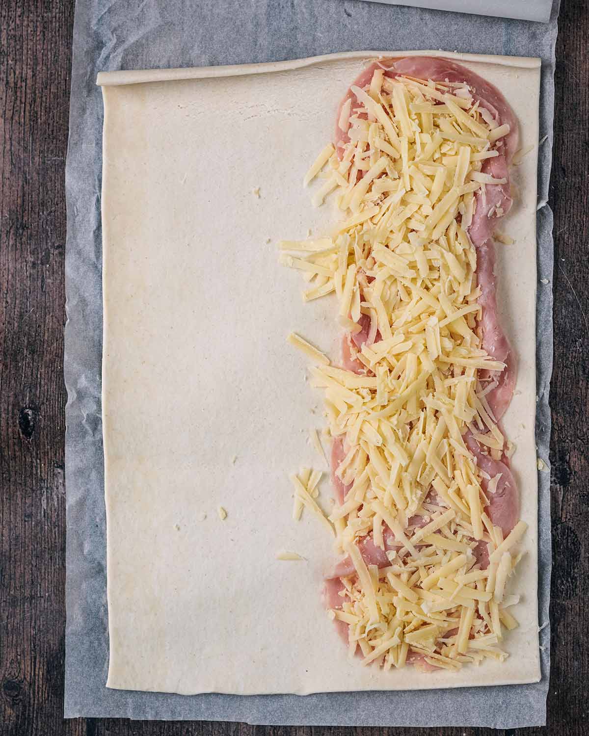 Slices of ham and grated cheese added to the sheet of pastry.