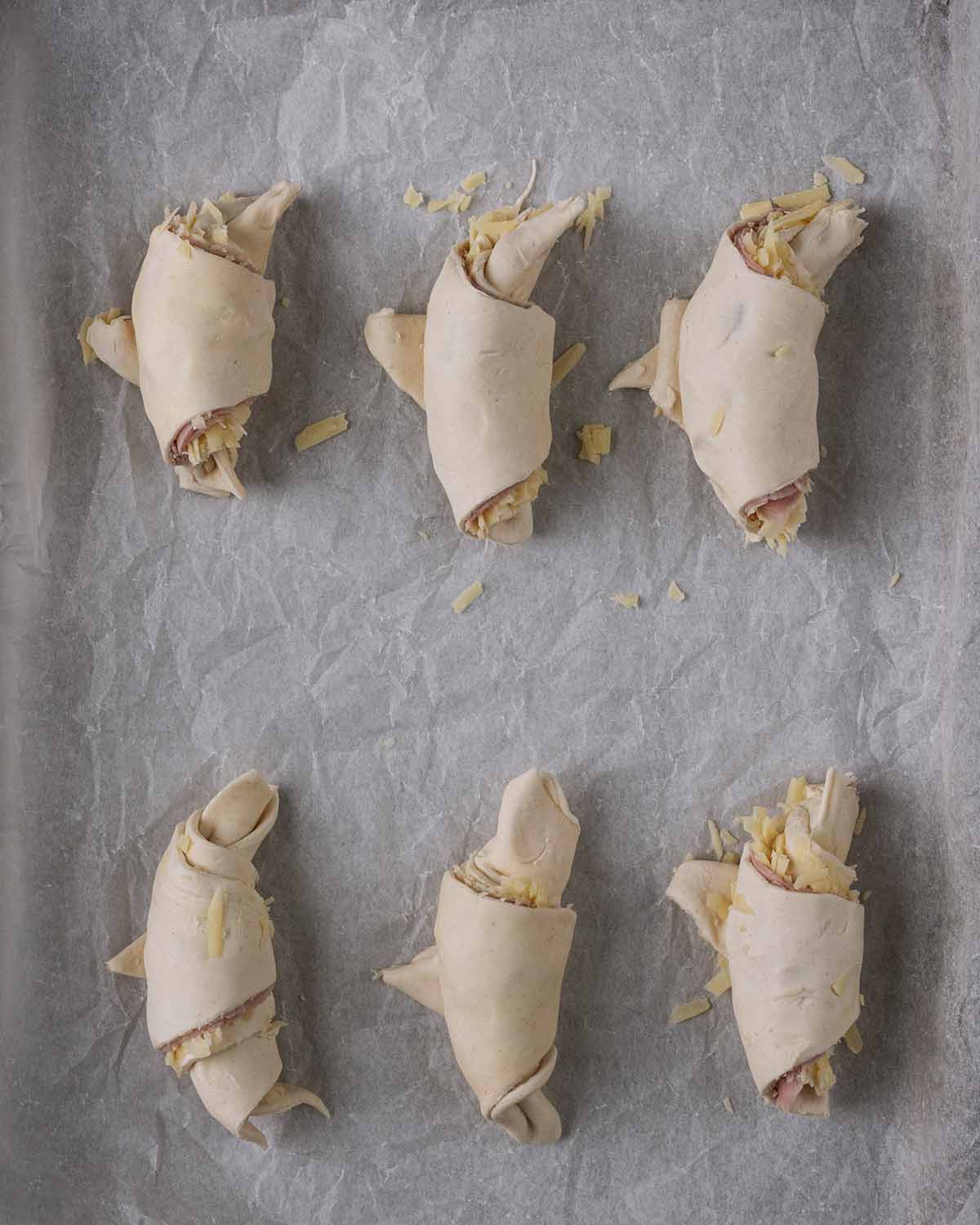 Uncooked croissants on a lined baking tray.