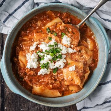 A bowl of slow cooker lasagna soup with a spoon in it.