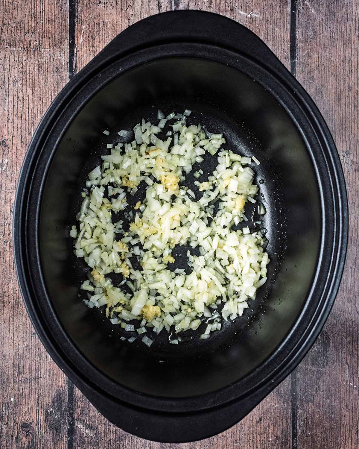 Cooked, chopped onions in a slow cooker bowl.