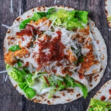 A chicken caesar taco on a wooden surface.