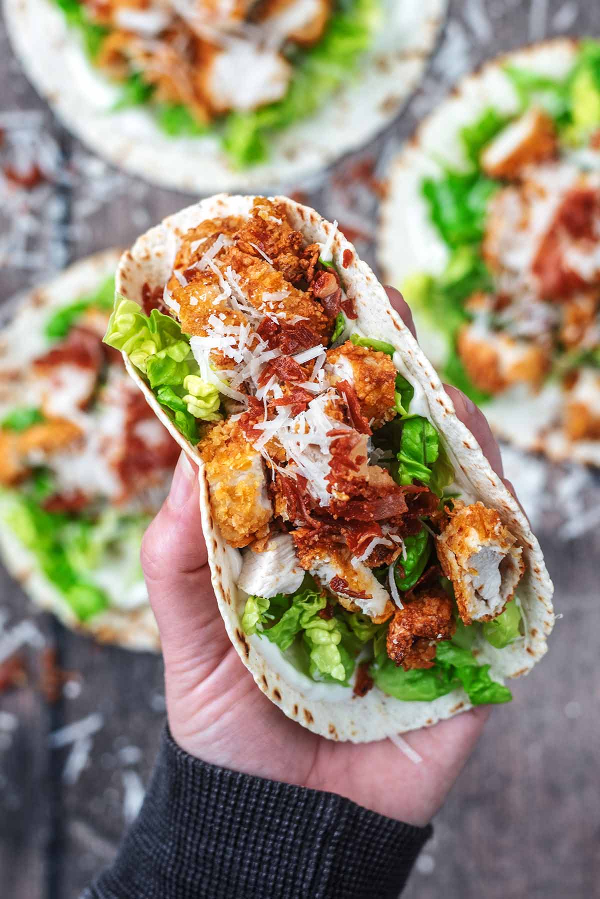 A hand holding a crispy chicken taco.